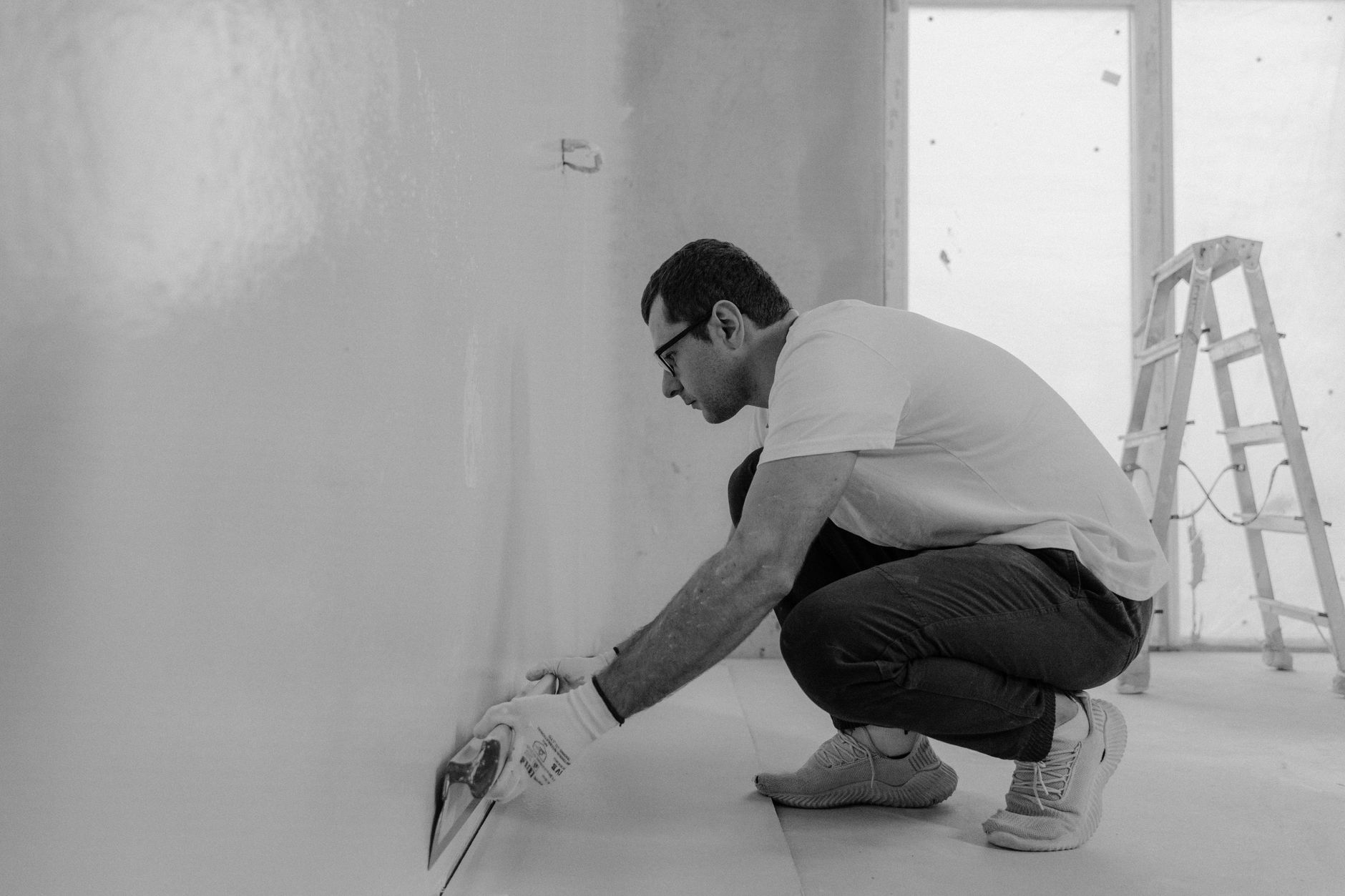 Homme qui rénove un mur intérieur avec des outils d’enduit