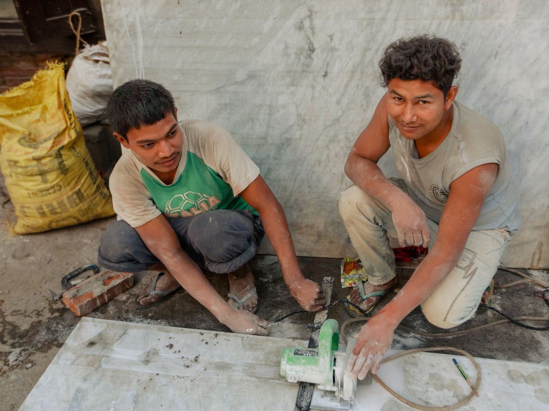 Deux artisans qui découpent du carrelage sur un chantier