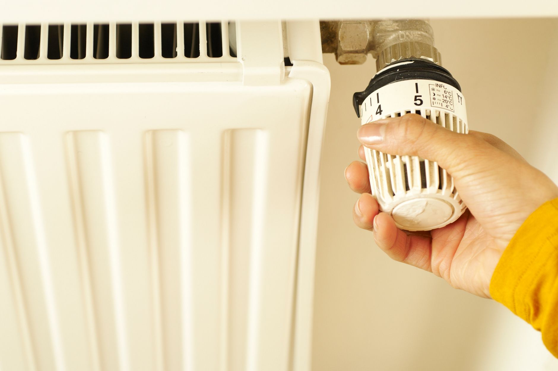Main qui règle le thermostat d'un radiateur