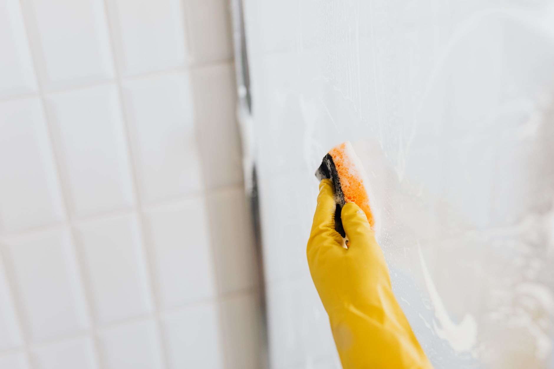 Main gantée qui lave une surface carrelée