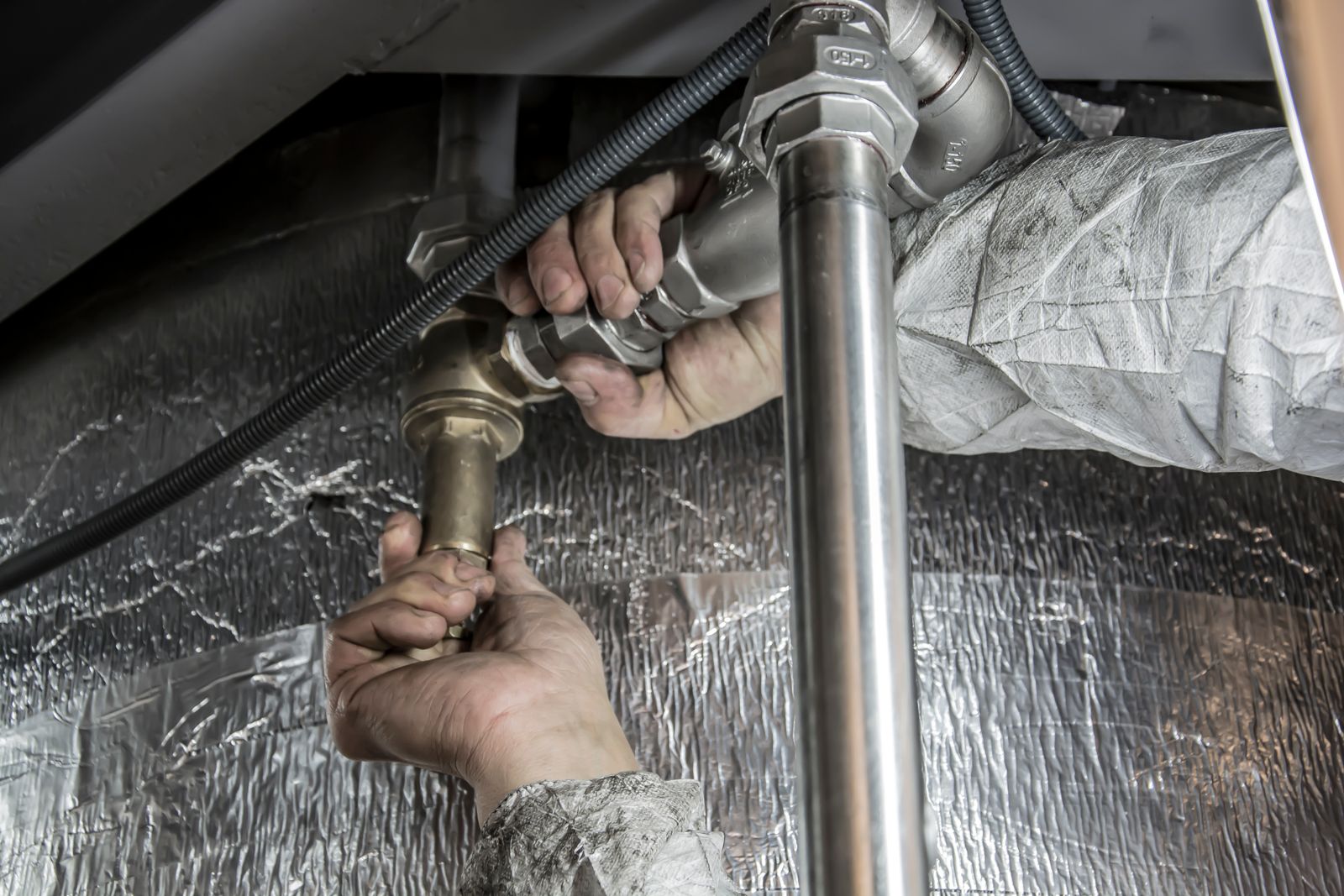 Mains d’un plombier posant des tubes en acier