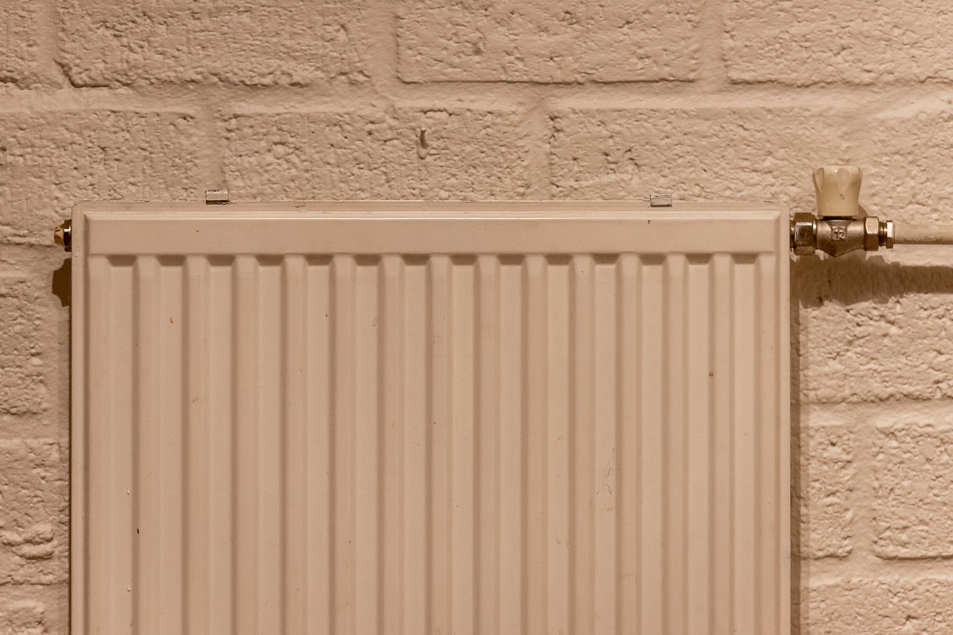 Radiateur blanc fixé sur un mur de brique