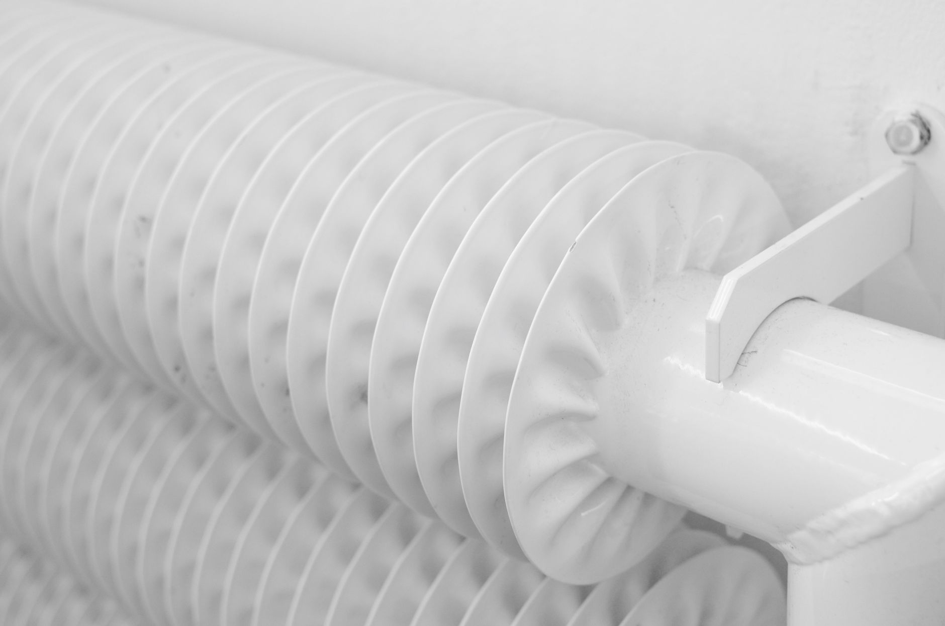 Radiateur tubulaire blanc relié à son tuyau