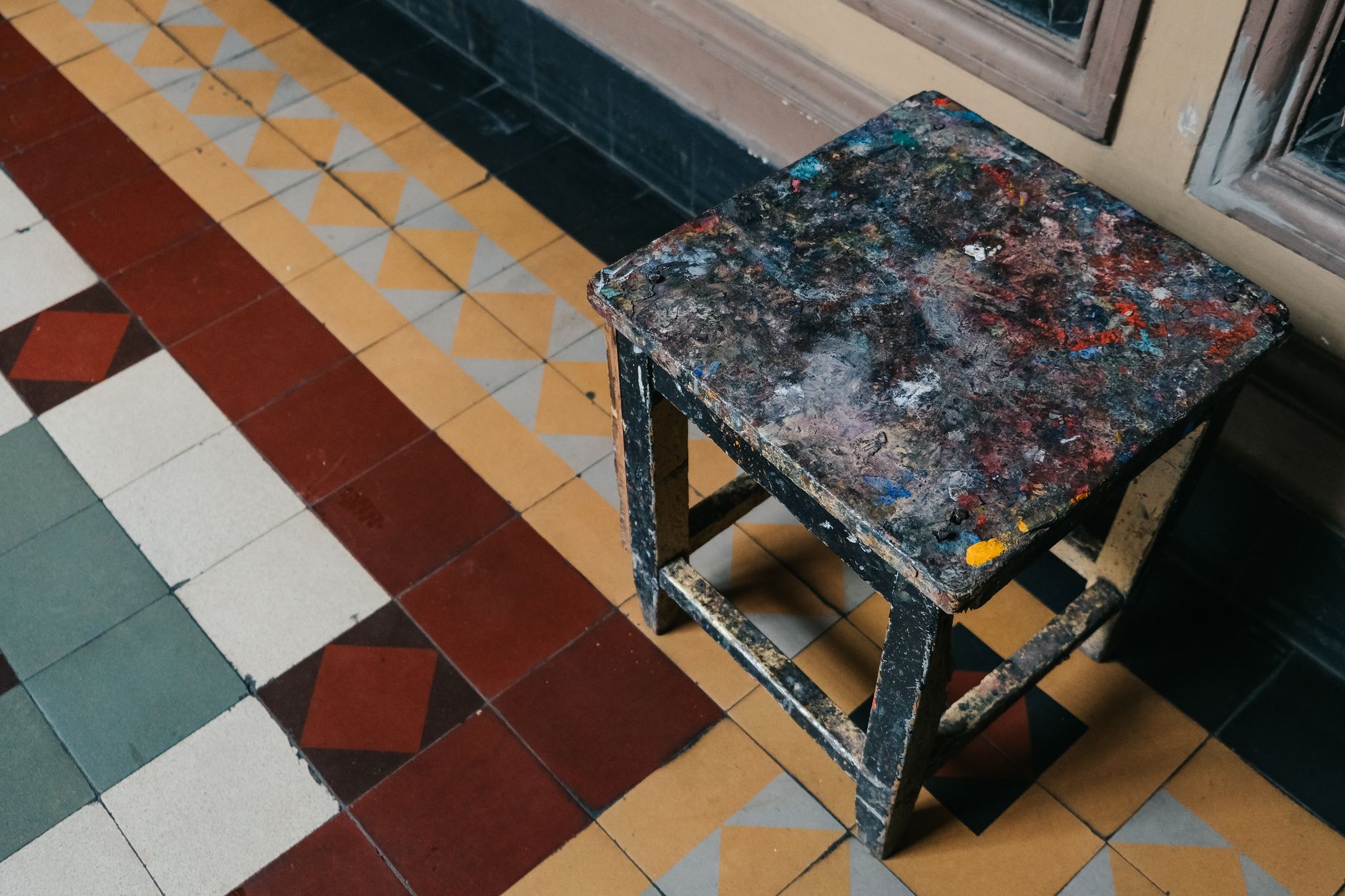 Tabouret taché de peinture sur un sol carrelé